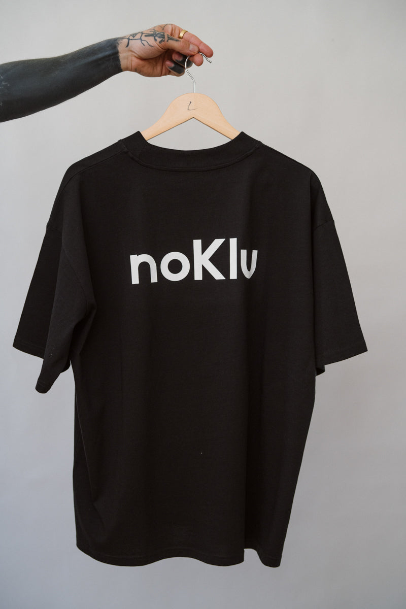 Black t-shirt with 'noKlu' text on a hanger against a gray background