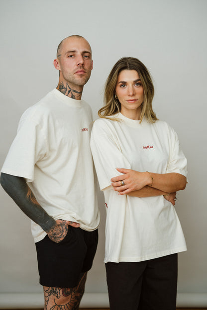 Two people wearing white t-shirts with a red logo against a plain background