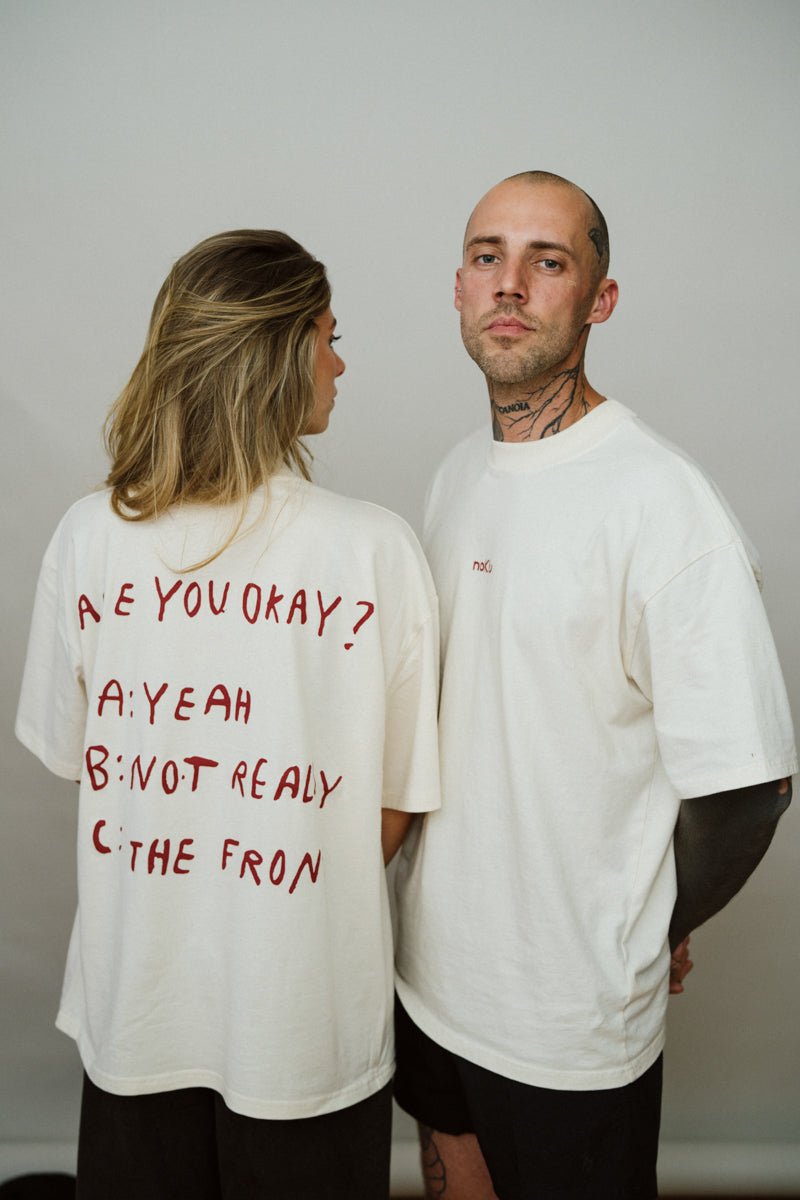 Two people wearing light beige  t-shirts with red text on a plain background