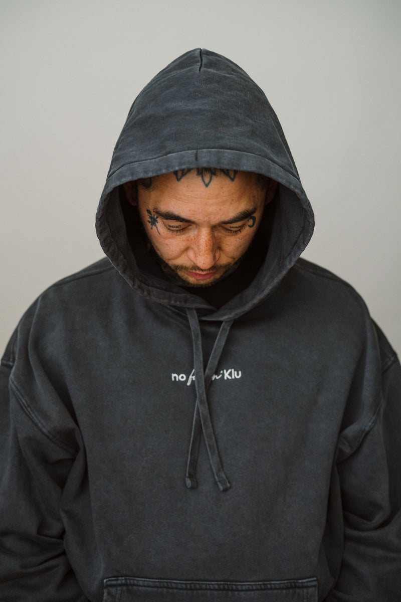 Person wearing a dark gray hoodie with a brand logo on a plain background