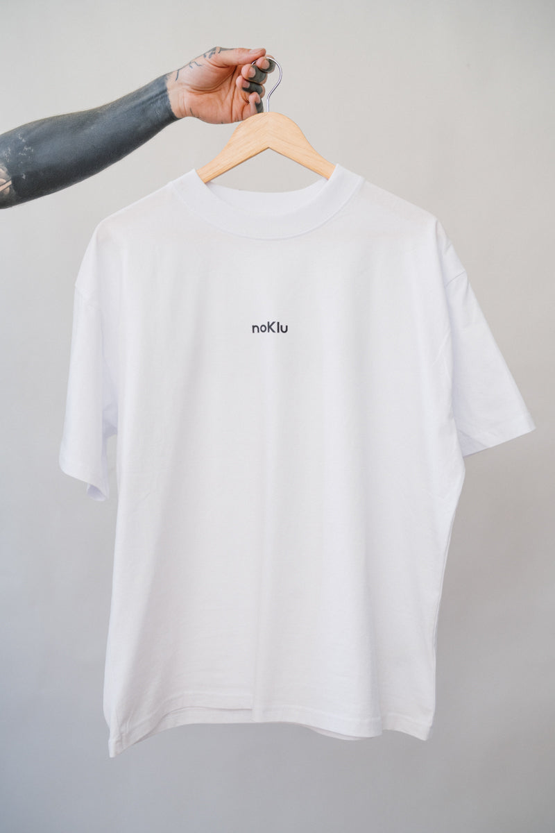 White t-shirt with 'noklu' logo on a hanger against a gray background