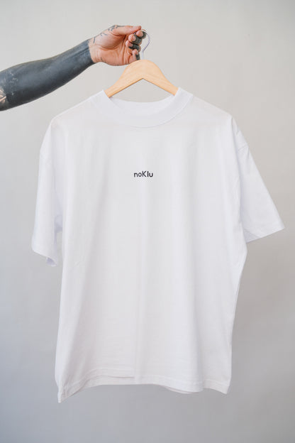 White t-shirt with 'noklu' logo on a hanger against a gray background