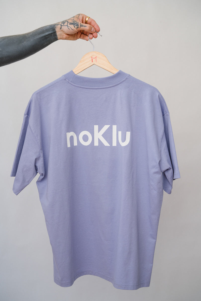 Purple t-shirt with 'noKlu' logo on a hanger against a gray background