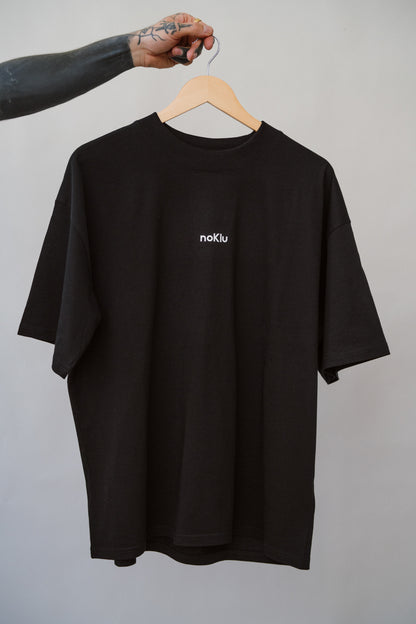 Black t-shirt with a logo on a hanger against a gray background