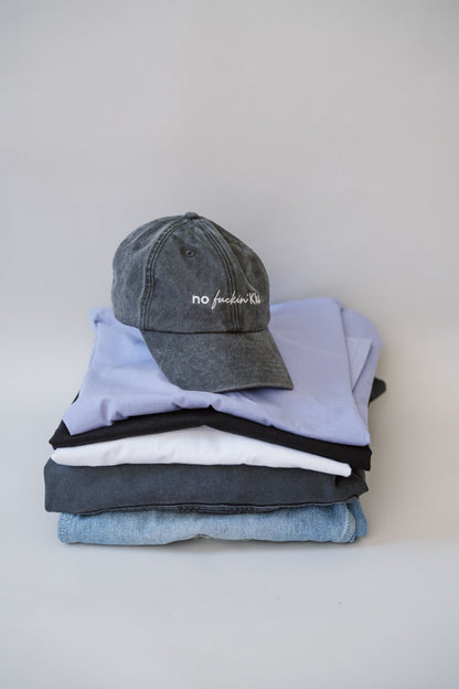 Stack of folded clothes including a cap on a light gray background